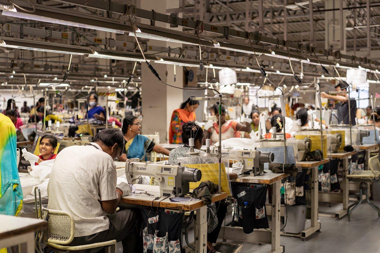Rows of tailors at sewing machines on the factory floor