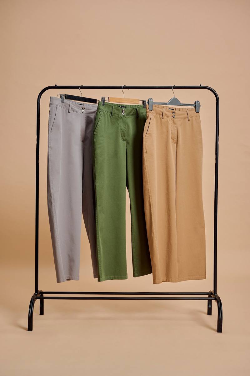 Trousers in grey, olive and tan on a rail