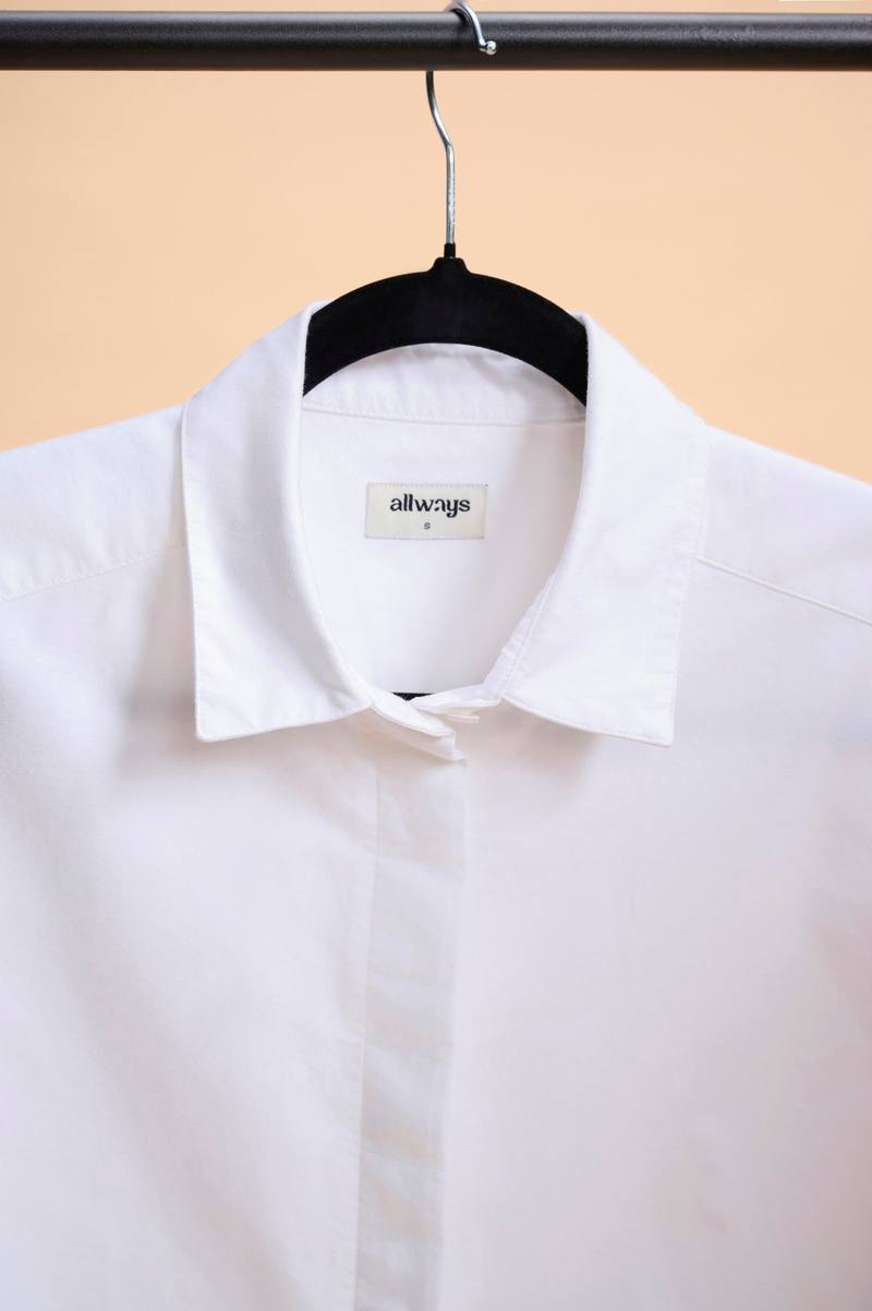 A white shirt on a hanger against a peach backdrop