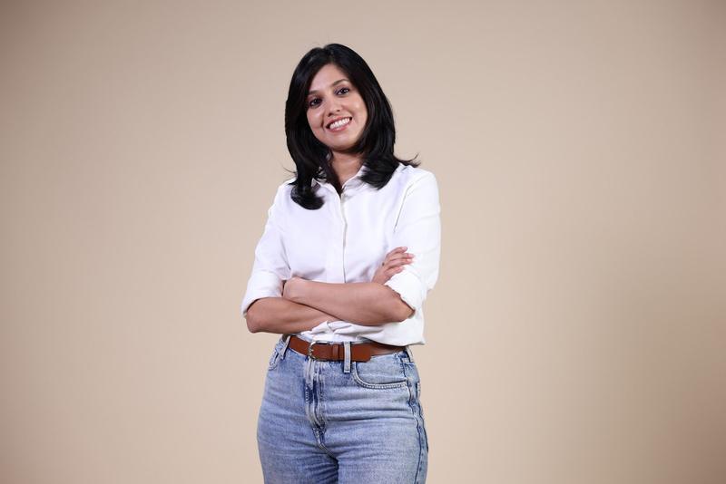 Yamini, founder of Allways, smiling with arms crossed, in a white shirt and jeans