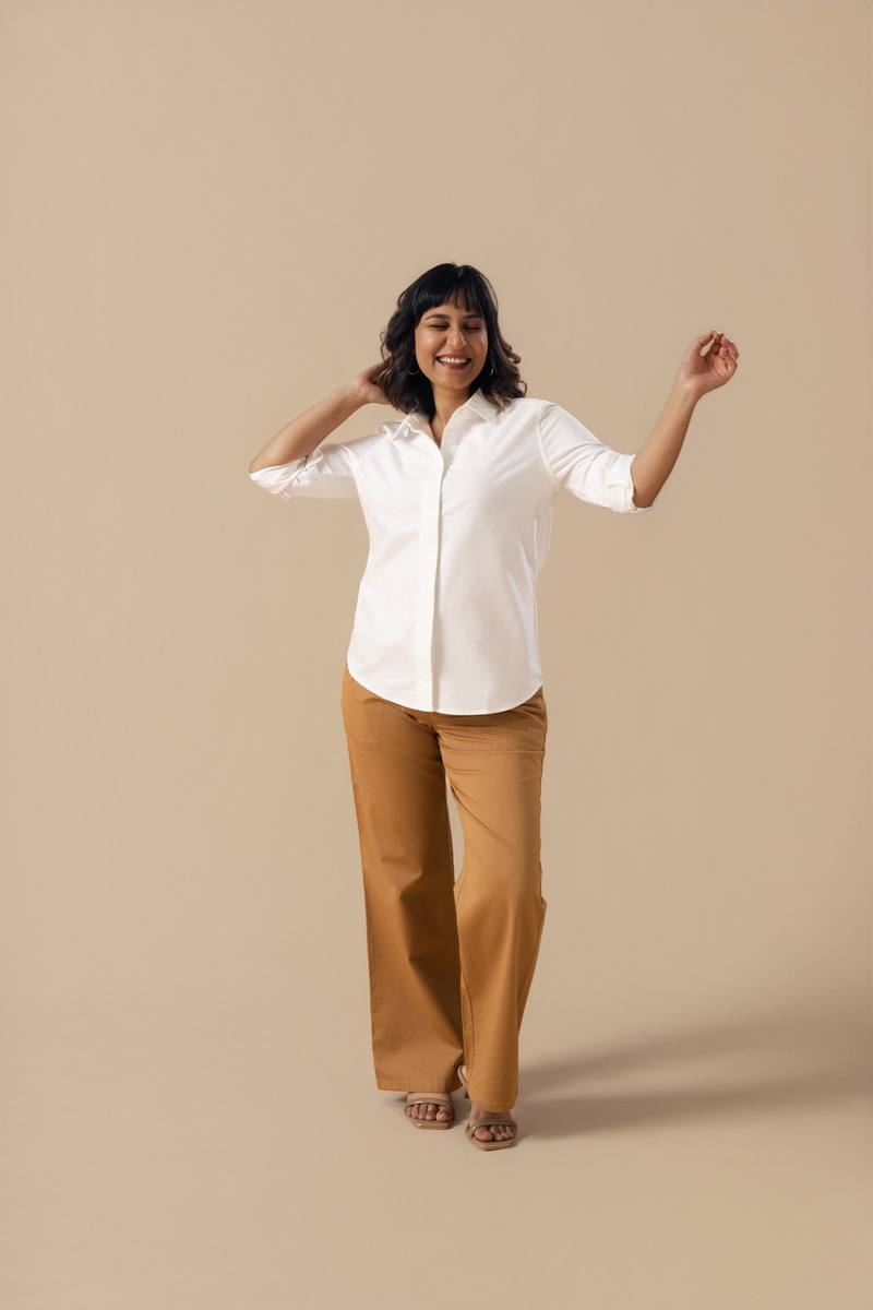 A woman in a white shirt and tan trousers in the studio