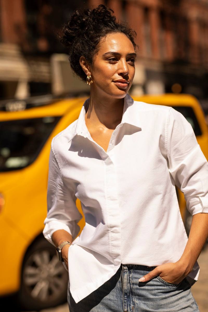 A woman in a white shirt on a New York street, a yellow cab behind her