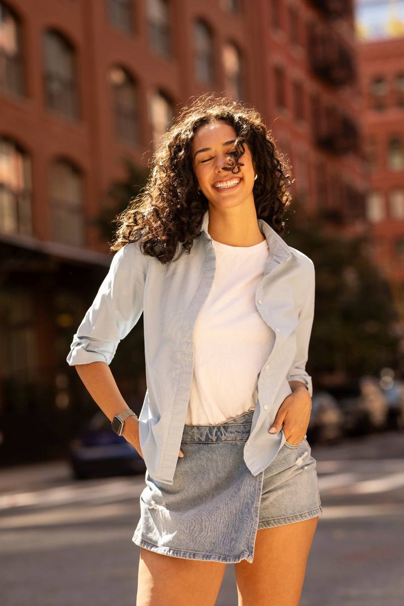 A woman in a light blue cropped shirt and denim skirt on a New York street