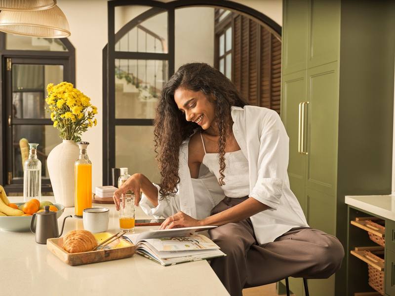 A woman in a white shirt reading at a breakfast table