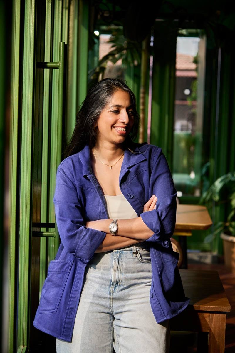 A woman in a blue chore jacket standing in a green doorway